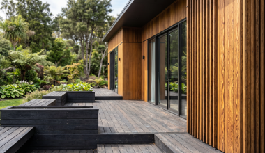 Thermory thermally modified wood decking and cladding on modern home exterior with lush green garden